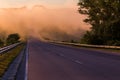 Dense early morning fog in wold at summer highway near river with guard rails Royalty Free Stock Photo