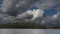 A dense forest grows on the hilly shores of a calm lake. Royalty Free Stock Photo