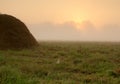 Dense morning fog over the meadow and haystack just after sunri Royalty Free Stock Photo