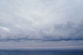 Dense storm clouds over the blue sea with a pink stripe of sunset Royalty Free Stock Photo