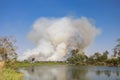 Dense white smoke rising from the raging wildfire and blue sky and Water source