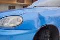 a dent on a car, a blue car with a damaged fender, the car is under warranty