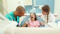 Dental assistant and dentist giving dental check up to little girl