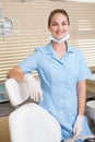 Dental assistant smiling at camera beside chair Royalty Free Stock Photo