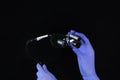Dental binocular glasses in hands. Gloved hands. Modern dentistry and the latest equipment. Photo on a black background
