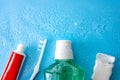 Dental care and oral hygiene concept with a bottle of green mouthwash, toothbrush, dental floss and tube of toothpaste soaked in Royalty Free Stock Photo