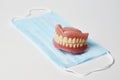 Dental dentures and medical mask on white background