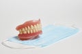 Dental dentures and medical mask on white background