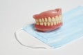 Dental dentures and medical mask on white background