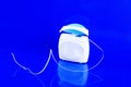 Dental floss in container on blue background Royalty Free Stock Photo