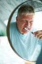 Dental health requires a certain routine. a senior man brushing his teeth in the bathroom mirror. Royalty Free Stock Photo