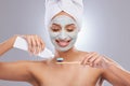 Dental hygiene is a must. an attractive young woman wearing a face mask and applying toothpaste to her toothbrush in the Royalty Free Stock Photo