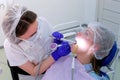 Dental hygienist makes ultrasonic cleaning dry teeth to woman in dentistry.