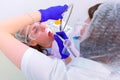 Dental hygienist makes ultrasonic cleaning teeth to young woman in dentistry.