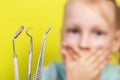 Dental instruments against the background of a frightened girl who covers her mouth with her hands. The concept of