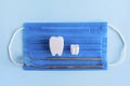 Dental instruments, equipment, mirror and probe, toy tooth, medical mask on blue background. Royalty Free Stock Photo