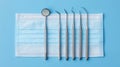 Dental instruments on a light blue background, with surgical masks underneath Royalty Free Stock Photo