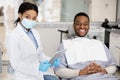 Dental Insurance Concept. Black Dentist Woman And Male Patient Posing In Clinic