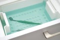 Dental mirror lies in green liquid for sterilization. Instrument is decontaminated