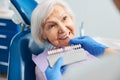 Dental professional matching tooth shade with pensioner teeth