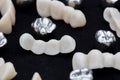 Dental silver metal tooth crowns and ceramic or zirconium tooth bridges on dark black surface. Royalty Free Stock Photo