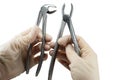 Dental surgical forceps to remove teeth in the hands of a dentist surgeon on a light white background