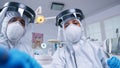 Dental team in coverall leaning over patient to work on patient gums