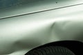 Dented sheet metal on the side of the silver car damaged in accident on the parking lot. Royalty Free Stock Photo