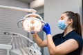 Dentist adjusts dental lamp to fit his needs.