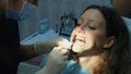 Dentist applies orthodontic glue on the teeth to the woman in the latch before installing the bracket system. Visit to