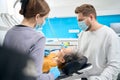 Dentist assistant holding saliva ejector during qualified dental therapist