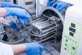 Dentist assistant`s hands get out sterilizing medical instruments from autoclave. Selective focus Royalty Free Stock Photo
