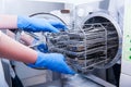 Dentist assistant`s hands get out sterilizing medical instruments from autoclave. Selective focus Royalty Free Stock Photo