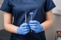 Dentist with blue gloves holding tools - dental mirror and dental probe at the dental office