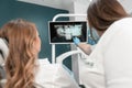 The dentist carefully analyzes the MRI image of the oral cavity in order to plan treatment. The patient receives an