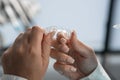 The dentist carefully holds the mouth guard in his hands, preparing for the procedure and demonstrating his adaptability