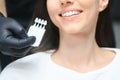 Dentist checking and selecting color of young woman's teeth