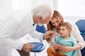 Dentist checking up little boy sitting in mother\'s lap