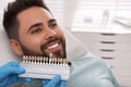 Dentist checking young man`s teeth color in clinic Royalty Free Stock Photo