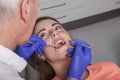 dentist checks gums and teeth of his patient with mirror and pro