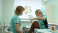 Dentist checks the teeth of a young woman with a mirror.