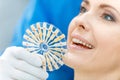 Dentist comparing teeth of smiling patient with samples