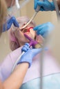 Dentist curing a woman patient in the dental office in a pleasant environment. Beautiful girl in dental chair on the