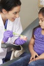 Dentist Demonstrating How To Brush Teeth To Young Female Patient