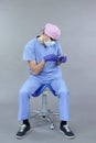 Dentist with dental instruments demonstrates typical unbalanced seated position at work