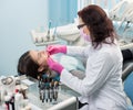 Dentist with dental tools - mirror and probe checking up patient teeth at dental clinic office. Medicine, dentistry