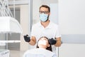 Dentist doctor with glasses drilling teeth to female patient