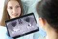 Dentist doctor holding digital tablet with teeth xray in front of patient