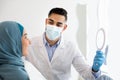 Dentist Doctor Showing Teeth Treatment Result To Muslim Female Patient, Holding Mirror Royalty Free Stock Photo