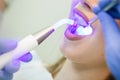 Dentist doing procedure with dental curing UV light in clinic